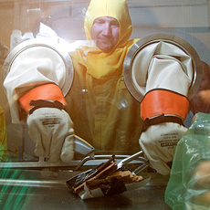 An SRS employee works to separate different types of waste within a glovebox; each waste stream will be disposed of using a different method.