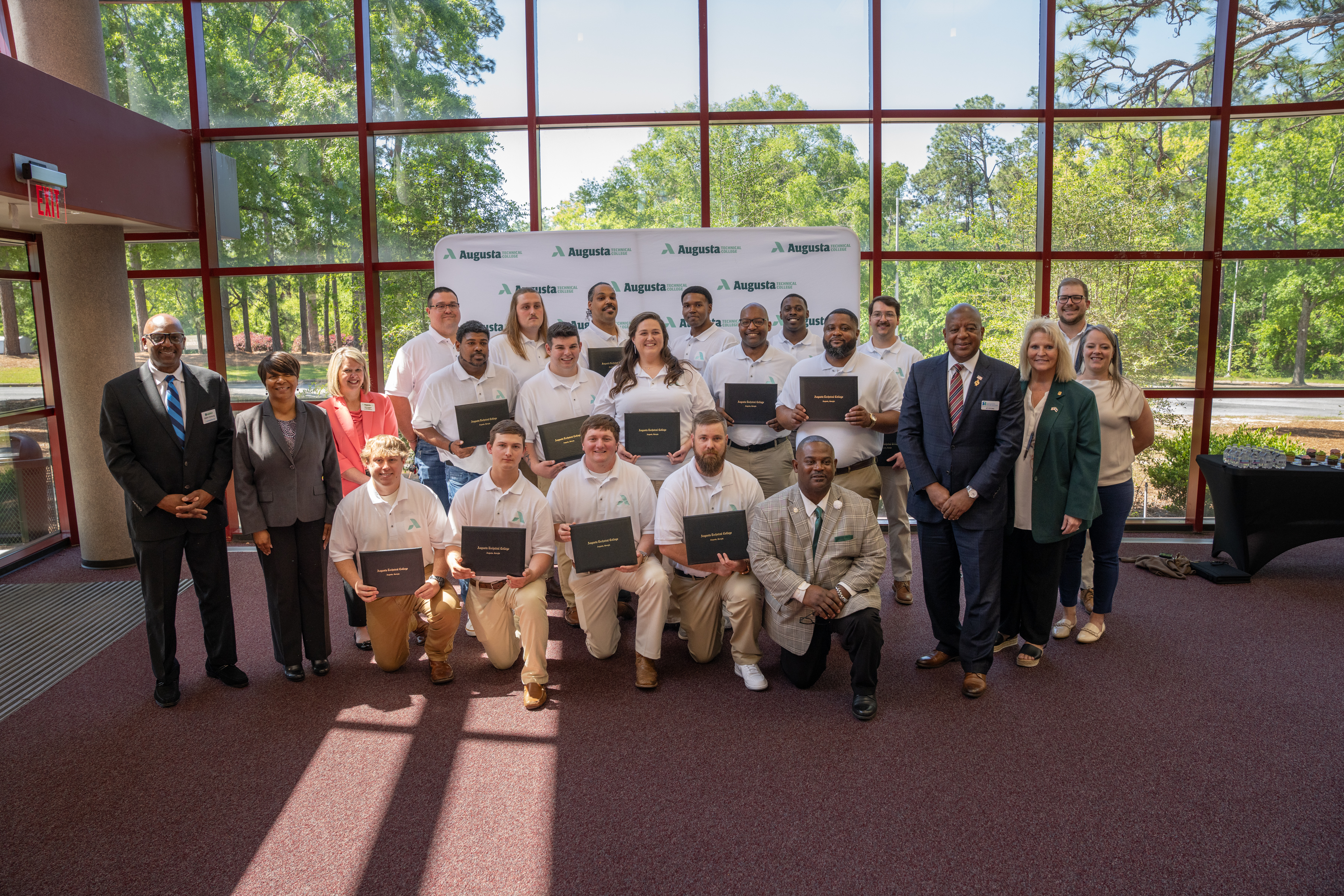 Front row: Garrett Wright; Paxton Wall; Gage Jones; Cameron Coughenour; Operations Training Lead David Jackson; (second row): Department of Energy-Savannah River Deputy Manager Edwin DeShong; Site Training Deputy Director National Nuclear Security Administration an Environmental Management Wendy Lark; Vice President of Economic Development, Augusta Technical College Julie Langham; Mario O’Neal; Gregory Davis; Kelly Coons; William Prather; Zedric Swedenburg; SRNS Senior Vice President NNSA Tritium Operations and Programs J.C. Epting; Program Manager and Manager of Youth Apprenticeships BooBoo Roberts; College Partnership and Pipeline Development Lead Abigail Bowman; (third row): Jacob Bridgmon; Cameron Leach; Anthony Harley; Malik Jones; Chad Gilchrist Jr.; Benjamin Parsons; Patrick Ott.